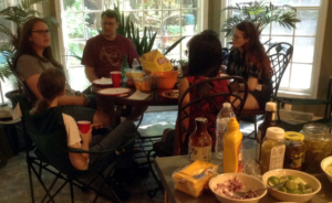 five people around a table with food and drinks